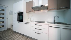A modern kitchen with white cabinets, a stainless steel oven, a kettle, and a sink. - Holiday Home Relax - One Bedroom Holiday Home with Hot Tub (Podstrana)
