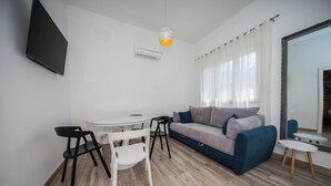 A modern living room with a sofa, a dining table, and chairs. - Holiday Home Relax - One Bedroom Holiday Home with Hot Tub (Podstrana)