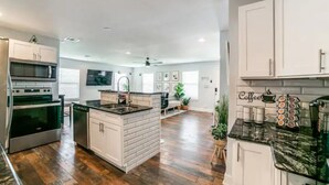 Una cocina amplia con una isla central, electrodomésticos de acero inoxidable y una zona de café.