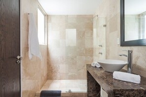 Un bagno con un lavandino capiente, un box doccia in vetro e una porta in legno scuro.