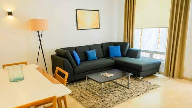 Ein modernes Wohnzimmer mit einer Eckcouch, einem Couchtisch, einem Esstisch und einer Lampe.