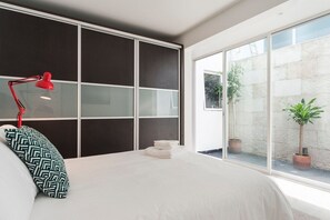 Una camera da letto con un letto grande, una lampada da scrivania rossa e vista all'esterno tramite una porta scorrevole in vetro.