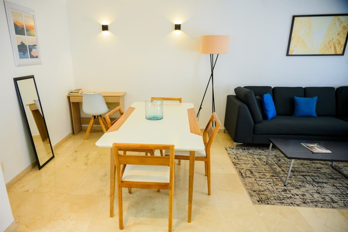 A compact living space with a dining table, chairs, a sofa, and a lamp.