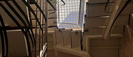 A staircase with metal railings and a view of a tiled floor through a window.