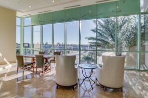 Enjoy a bright and airy space with a high ceiling, large windows, and a view of palm trees and the urban landscape.
