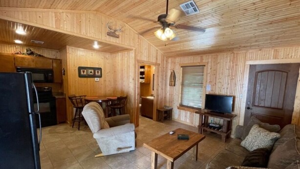 A wooden interior with a kitchen, dining area, and living room. - Antler Ridge Cabin #4 (Sulphur)