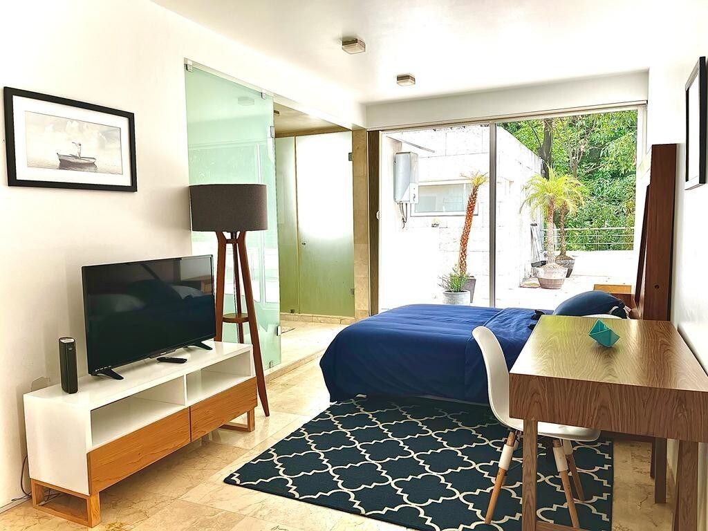 Une chambre d’hôtel moderne équipée d’un lit, d’un bureau, d’une télévision et d’une grande fen être donnant sur l’extérieur.