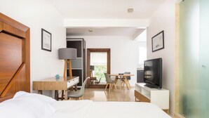 A hotel room with a bed, desk, chair, television, and a view of the outdoors. - Condesa Residence Amsterdam G (CDMX)