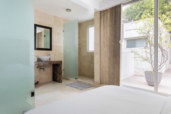 A modern bathroom with a glass shower enclosure, a sink, and a large window.