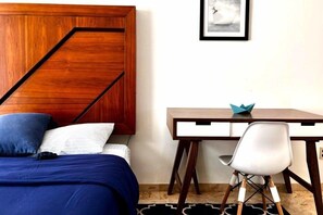 A bedroom with a bed, a desk, and a chair.