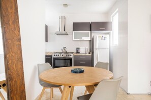 A modern kitchen with a round wooden table and chairs, a stove, oven, microwave, and refrigerator.