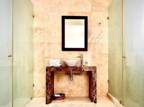 Un bagno con un elegante top in marmo, un lavabo, uno specchio e un box doccia.