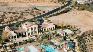 Vista aérea de un resort con varias piscinas, palmeras y un paisaje desértico.