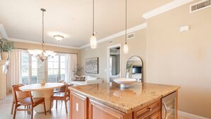 Una cocina con encimera de granito, armarios de madera e iluminación colgante.