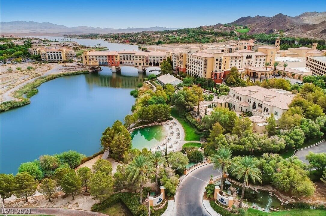 A hotel complex with multiple buildings, a central courtyard, and a body of water.