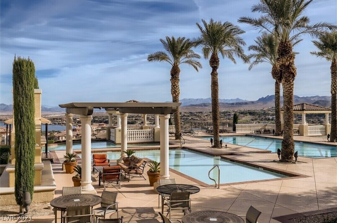 A rooftop pool area with palm trees, a pergola, and outdoor seating.