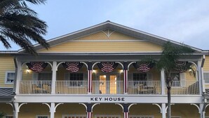 Ett tvåvåningshus i Key West-stil med en gul fasad, vita balkonger och amerikanska flaggor.