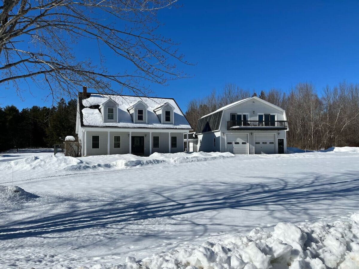 Una casa de dos pisos con garaje, rodeada de nieve.