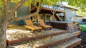 A deck with two lounge chairs, a hot tub, and a staircase leading to a covered area. - Spacious home near old mill w/pool table & hot tub (Bend)