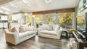 A spacious living area with two white sofas, a wooden coffee table, and a kitchen in the background. - Spacious home near old mill w/pool table & hot tub (Bend)