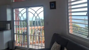 Ein Wohnzimmer mit einer Couch, einem Mülleimer und einer Glastür zum Balkon.