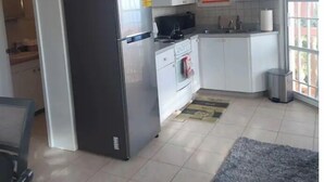 Eine moderne Küche mit weißen Schränken, einem Edelstahlkühlschrank, einem Herd und einer Spüle.