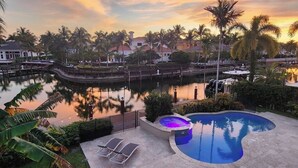 A pool area with a hot tub, lounge chairs, and a view of a body of water and palm trees. - On The Bay With Hot Tub, Pool, Kayaks And More (Hollywood)