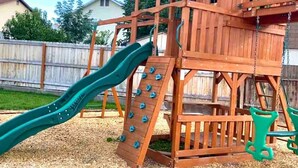 Eine hölzerne Spielkonstruktion mit Rutsche und Kletterwand.
