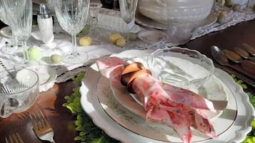 Una mesa de comedor dispuesta con cristalería transparente, una tureen de cerámica blanca y un centro de mesa decorativo.