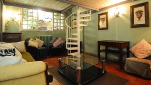 Una sala de estar con una mesa de centro de vidrio, una escalera en espiral y un radiador.