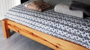 A bed with a patterned bedspread, a wooden headboard, and a nightstand with a lamp. - The bakery lives in the countryside near hiking trails (Val-Couesnon)