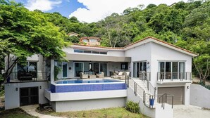 A modern two-story house with a swimming pool, a covered patio, and a view of the surrounding forest. - Amigos de Tortuga • 4 BR Villa • Private Pool • Oceanview (Playa Hermosa)