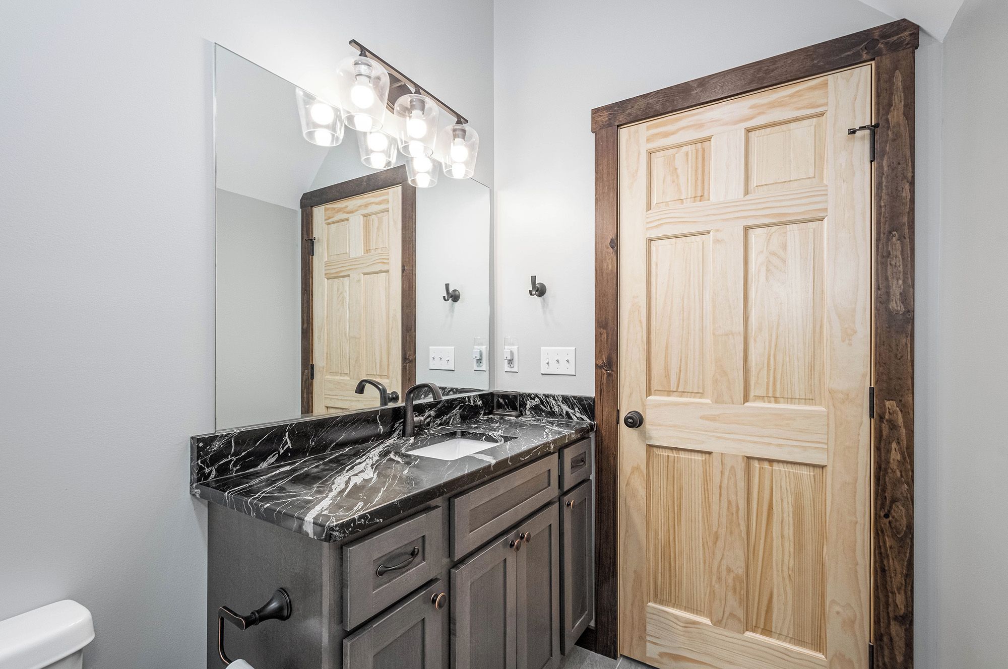 A bathroom with a marble sink, a mirror, and a wooden door.