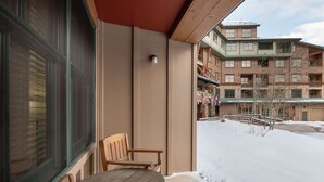 A balcony with wooden chairs, a window, and a view of a multi-story building with flags. - Premium Unit 1108 - One Bedroom - Zephyr Mountain Lodge 1 Condo (Winter Park)