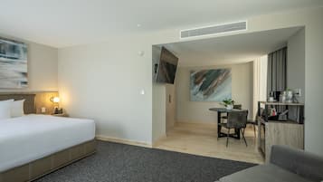 Ett hotellrum med en säng, ett skrivbord, en stol, en soffa och en tavla på väggen.