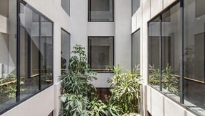Un edificio moderno con amplios ventanales y un patio central con plantas.