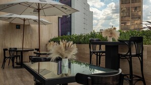 Un espacio exterior para comer con mesas y sillas, sombrillas y una decoración floral.