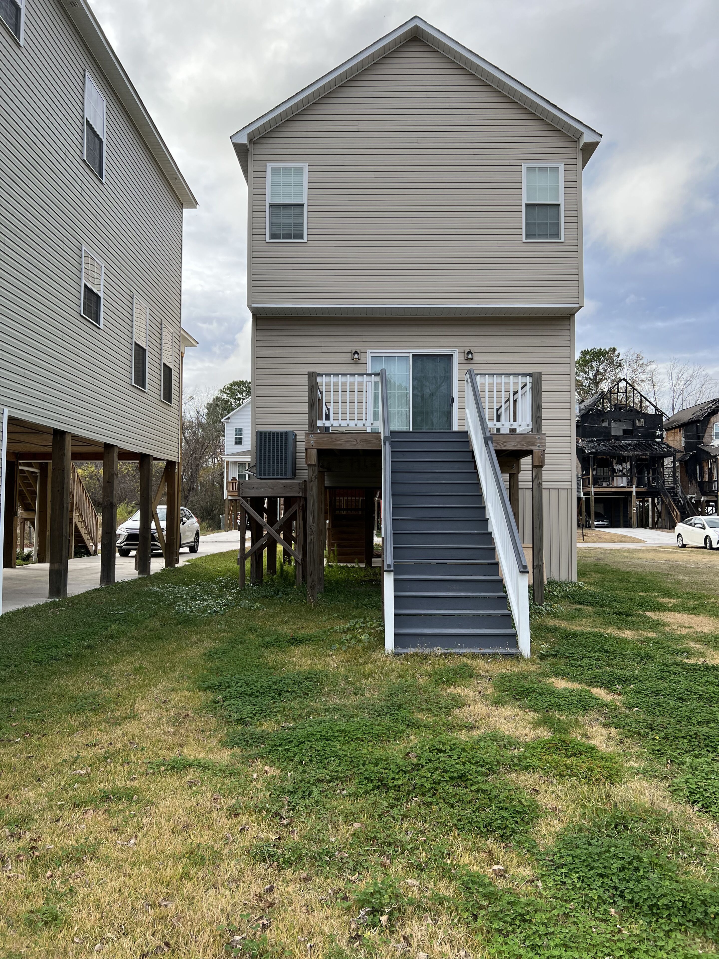 A two-story residential building with a front porch and a staircase leading to the entrance.