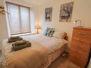 Une chambre à coucher avec un lit, une commode, une lampe et des œuvres d’art accrochées au mur.
