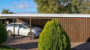 A modern building with a covered car parking area, a gravel driveway, and neatly trimmed shrubs. - The Comfort of This Cottage Merges With Nature (Holbaek)