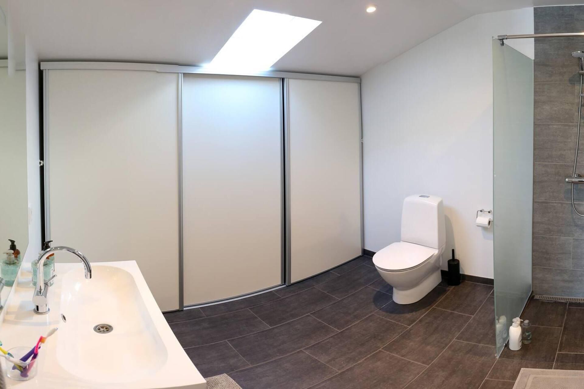 A modern bathroom with a curved sink, a toilet, and a shower area.