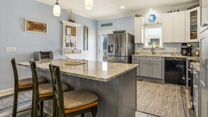 A kitchen with a central island, a refrigerator, a coffee maker, and a dishwasher.
