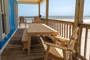 A wooden deck with a table and chairs, overlooking a beach. - Blue Sky Breeze - 102 Tampico 4 Bedroom Home by RedAwning (Dauphin Island)