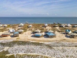 A coastal area with beachfront houses, some elevated on stilts, and a clear view of the ocean. - Blue Sky Breeze - 102 Tampico 4 Bedroom Home by RedAwning (Dauphin Island)