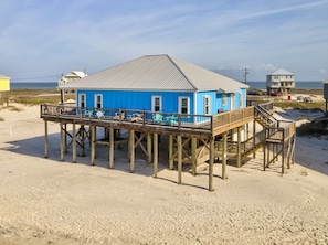 A blue building with a deck, wooden stilts, and a view of the beach. - Blue Sky Breeze - 102 Tampico 4 Bedroom Home by RedAwning (Dauphin Island)