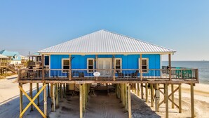 A blue building with a wooden deck on stilts, a sign reading 'Blue Sky Breeze,' and a view of the ocean.