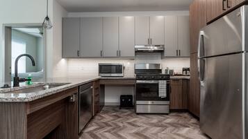Una cocina moderna con armarios grises, electrodomésticos de acero inoxidable y un suelo con estampado en espiga.