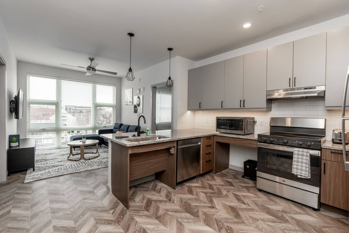 A modern kitchen with a herringbone floor pattern, stainless steel appliances, and a built-in oven.