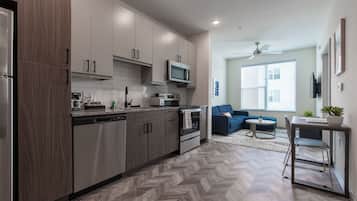 Una cocina moderna con piso de parquete, electrodomésticos de acero inoxidable y muebles de madera clara.