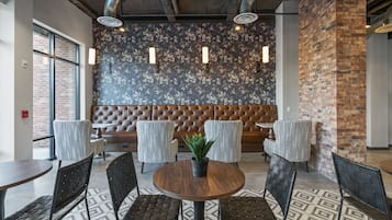 A modern interior with a round wooden table surrounded by black chairs, a brown cushioned bench, and a patterned floor.